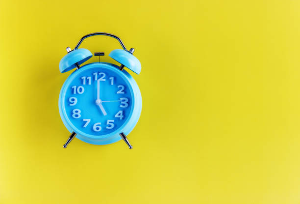 istock Blue alarm clock on yellow background. Top view. Copy space for text. 1300302294