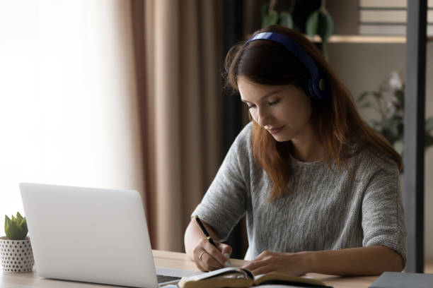 istock Millennial female student in headphones study at home 1300302704