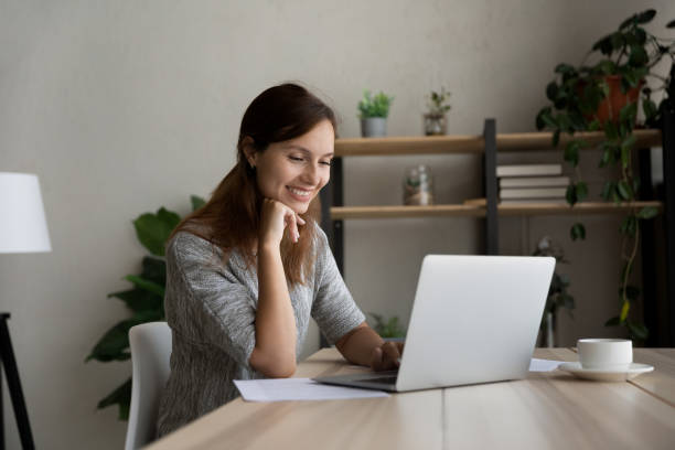 istock Smiling woman work distant on laptop at home 1300302716