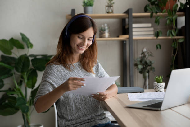 istock Smiling young woman work at home reading paperwork 1300302722