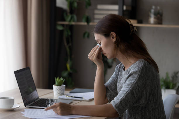 istock Exhausted young woman suffer from migraine working on laptop 1300302742
