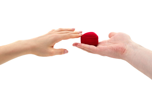 A male hand gives a box in the form of a heart to a female isolated on a white background.