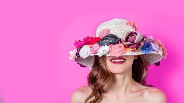 Beautiful smiling woman in elegant hat on pink background