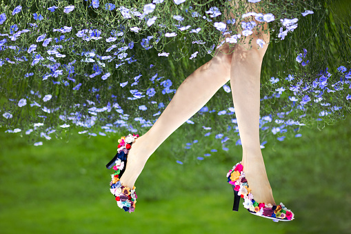 Beautiful female legs wearing shoes decorated with flowers and flower natural skirt. Mother nature concept