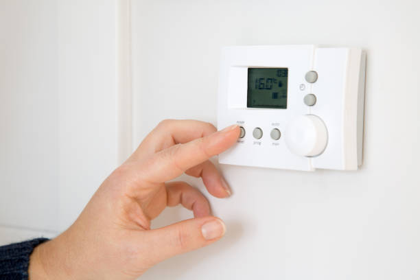 istock Woman adjusting digital central heating thermostat at home 1300305387