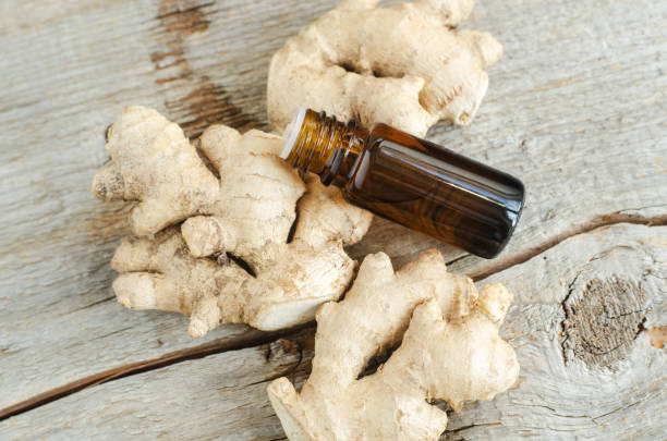 istock Small bottle with essential ginger oil (extract, tincture, infusion, perfume). Aromatherapy, spa and herbal medicine ingredients. Old wooden background. Copy space 1300307383