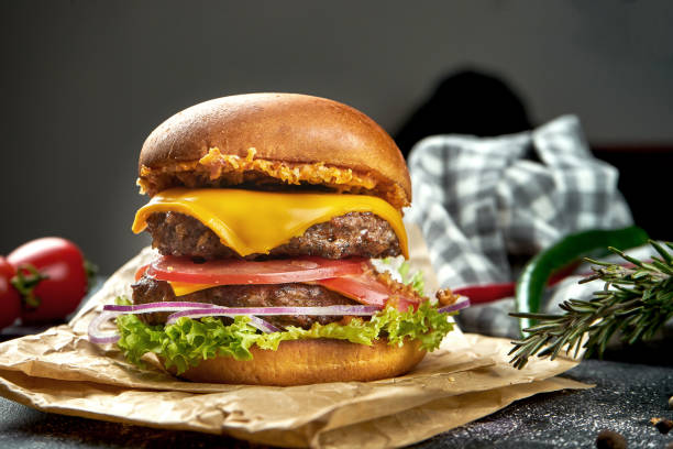 istock Juicy double burger with beef, tomatoes, cheese and crispy onions on a dark background. 1300307449