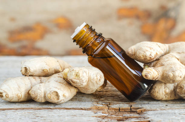 istock Small bottle with essential ginger oil (extract, tincture, infusion, perfume). Aromatherapy, spa and herbal medicine ingredients. Old wooden background. Copy space 1300307534