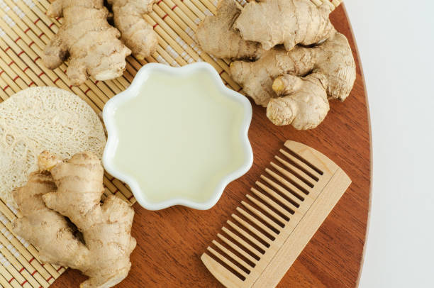 piccola ciotola con succo di zenzero (estratto, tintura, infuso, profumo) e spazzola per capelli in legno. aromaterapia, spa e cura naturale dei capelli. lay piatto, spazio di copia - oli aromi e spezie foto e immagini stock