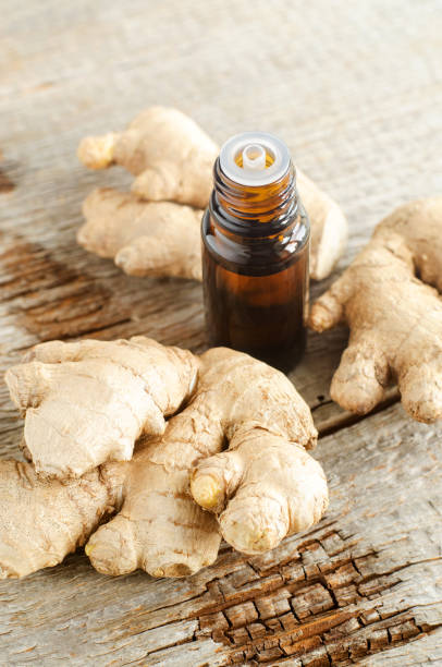 istock Small bottle with essential ginger oil (extract, tincture, infusion, perfume). Aromatherapy, spa and herbal medicine ingredients. Old wooden background. Copy space 1300307603