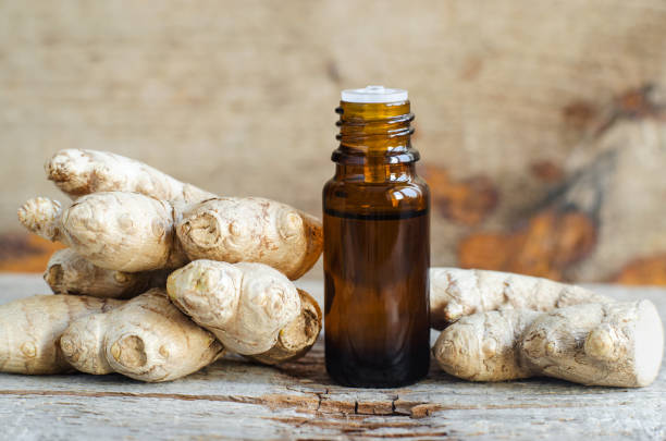 Small bottle with essential ginger oil (extract, tincture, infusion, perfume). Aromatherapy, spa and herbal medicine ingredients. Old wooden background. Copy space