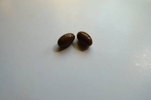 istock 2 glossy brown softgel capsules of vitamin D3 1300308186