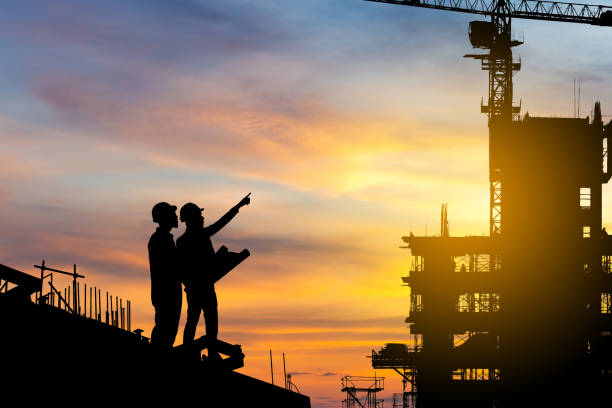 istock Silhouette of Engineer and worker checking project at building site background, construction site at sunset in evening time 1300309127