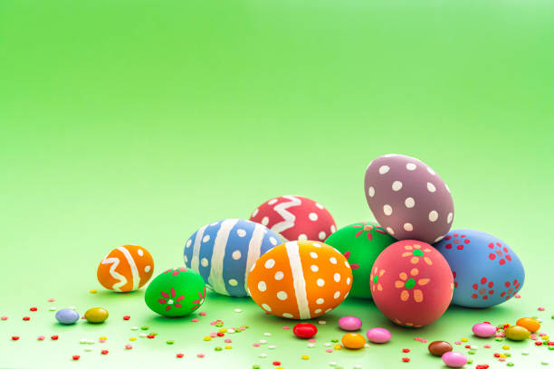 istock Colorful Easter eggs with candies and sugar sprinkles on green background. Copy space 1300309784