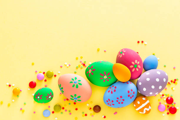 istock Colorful Easter eggs with candies and sugar sprinkles on yellow background. Copy space 1300309828