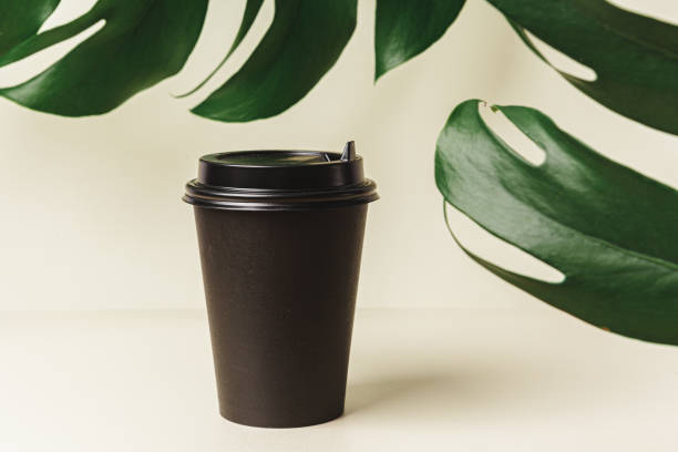 istock Disposable paper coffee cup and green leaf 1300313663