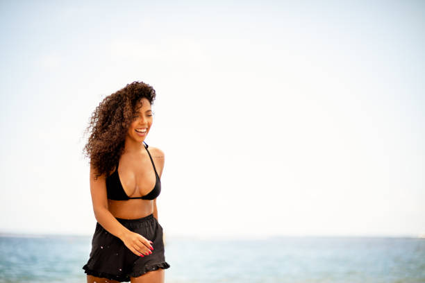 istock Young woman laughing while walking along a beach 1300315278