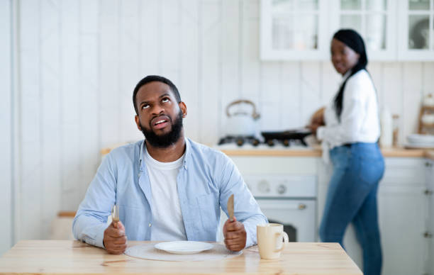 istock Impatient hungry black husband waiting for dinner with empty plate, looking bored 1300315856