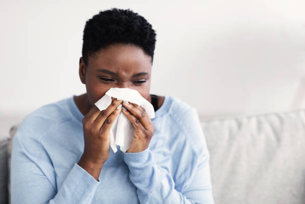 istock Sick black woman sneezing, holding tissue paper 1300315865