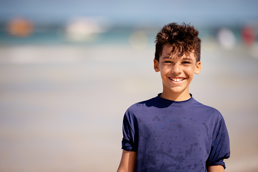 Portrait of a young boy smiling while enjoying a day at the beach in the summer