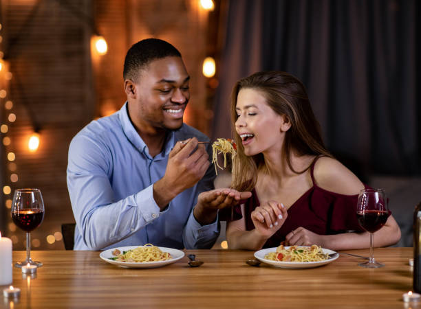 istock Romantic Interracial Couple Having Fun During Dinner In Restaurant, Eating Spaghetti Together 1300317630
