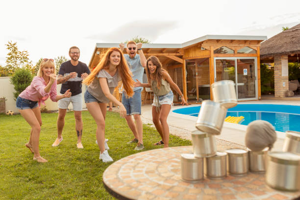 istock Man throwing a ball knocking down pyramid of tin cans while at a party 1300317717