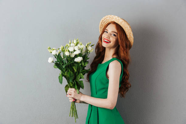 istock Redhead young cheerful woman with flowers. 1300319150