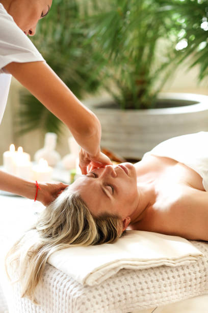 istock Asian masseuse massaging face of client 1300321368