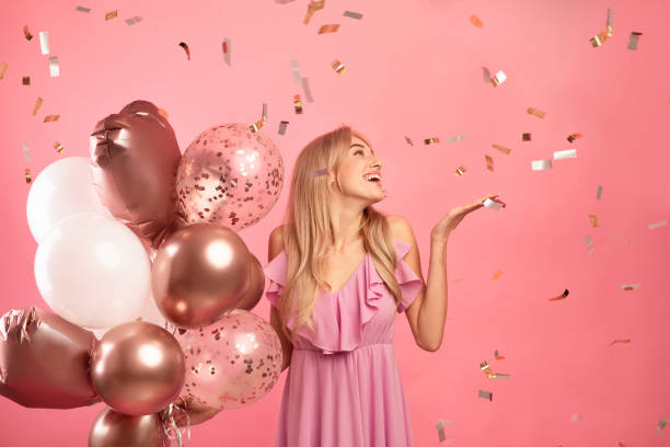 charmig ung dam som håller ballonger, med födelsedagsfest över rosa bakgrund med fallande konfetti, fritt utrymme - kvinna ballonger bildbanksfoton och bilder