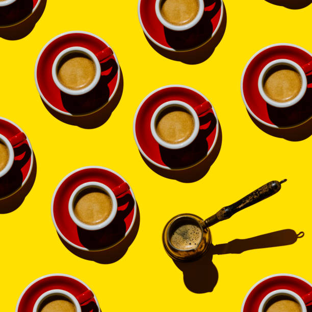 istock Espresso coffee in red cup and copper cezva on yellow background Pattern 1300324502