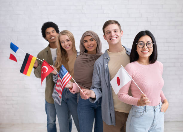 Exchange students and language school for different people Exchange students and language school for different people. Funny digital young international pupils holding flags of USA, Japan, Turkey, Germany and France in classroom, studio shot, empty space exchange student stock pictures, royalty-free photos & images