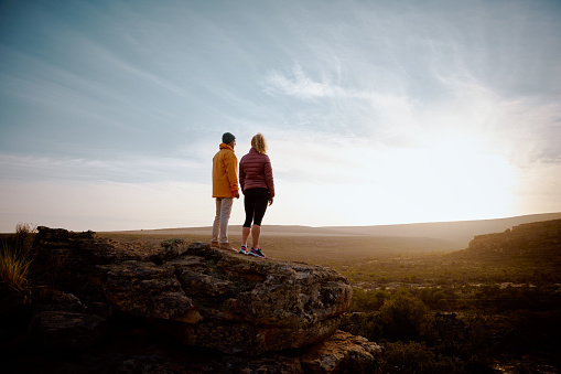 Young couple standing at mountain peak watching sunrise