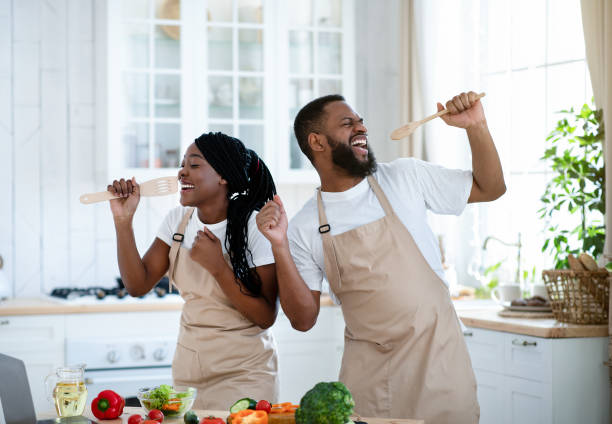 Kitchen Concert. Cheerful Black Couple Having Fun While Cooking Together At Home