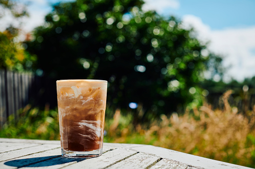 Glass of Iced Coffee with cream on a Garden table during a sunny summers day.