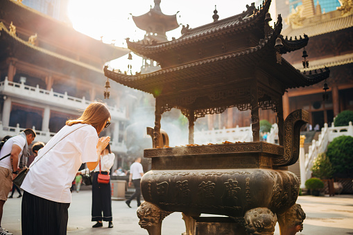 Woman praying at the Jing'an Temple which is one of the most famous temples in Shanghai which is located at West Nanjing Road, Jing'an District, the flourishing downtown area of Shanghai. In 1983, it was put on the list of key national protection.