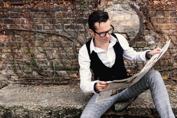 istock Mid adult man reading newspaper while relaxing outdoors. 1300329491