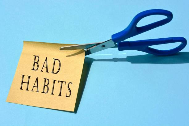 scissors that cut yellow notepad with bad habits text on a blue background. spending concept - bad habit imagens e fotografias de stock