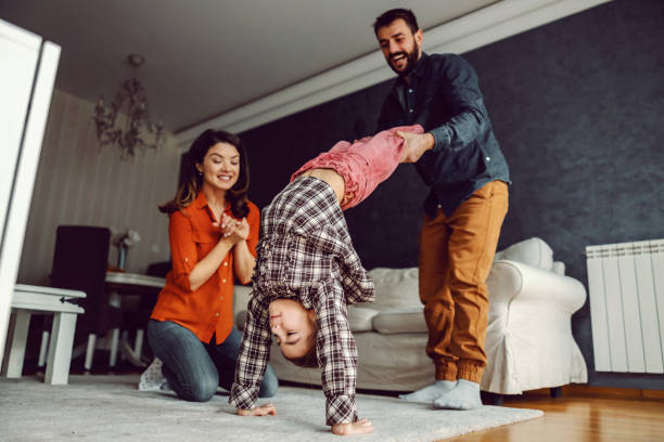 istock Father playing with his daughter and teaching her how to make headstand. Mother kneeling next to them and watching with smile on her face. 1300331577