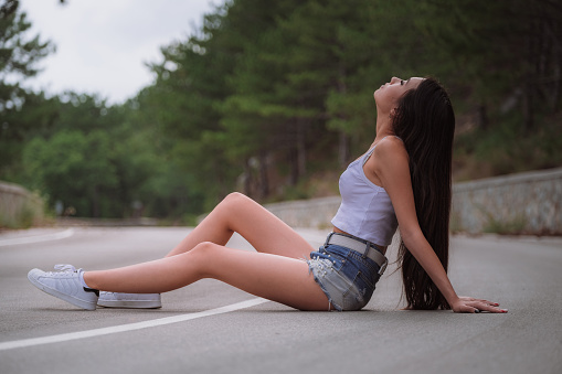 Beautiful young woman travels through a mountainous area. The concept and idea of a summer holiday, hitchhiking, finding your own way