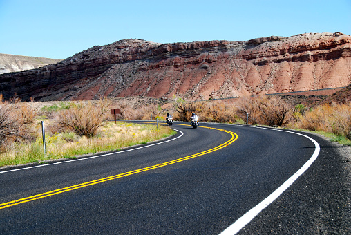 motorcycle riding in desert on empty highway through red rock mesa and scenic landscape