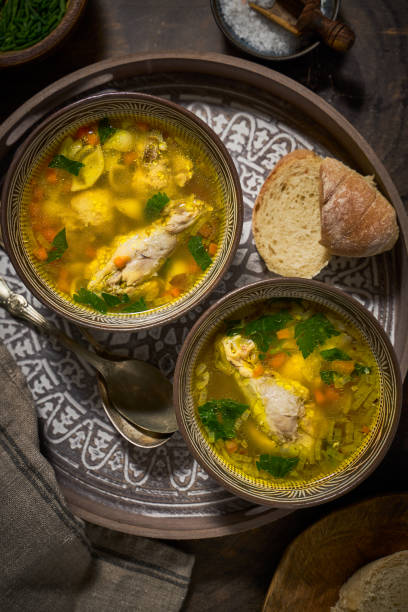 istock Asian style chicken soup in two clay bowls, bread, top view 1300333185