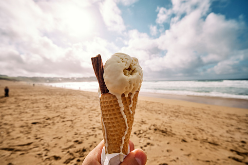 Hand holding an Ice cream at Fistral Beach, Newquay, Cornwall on a sunny Autumn day.