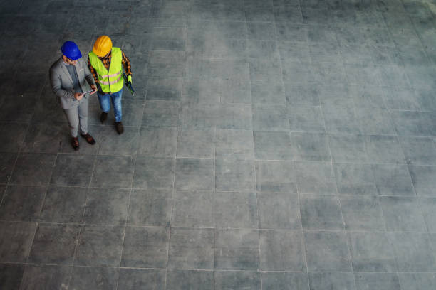 istock Aerial view of architect and construction worker standing on site and discussing about project. 1300333691