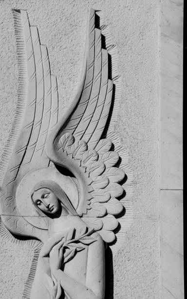angelo scolpito in un muro di pietra in un cimitero solitario - sentinels of the tomb foto e immagini stock