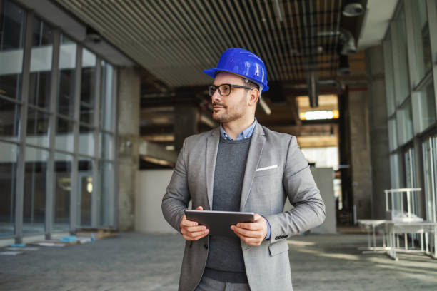 istock Architect standing in building in construction process and checking on works. He is having tablet in his hands. 1300334805