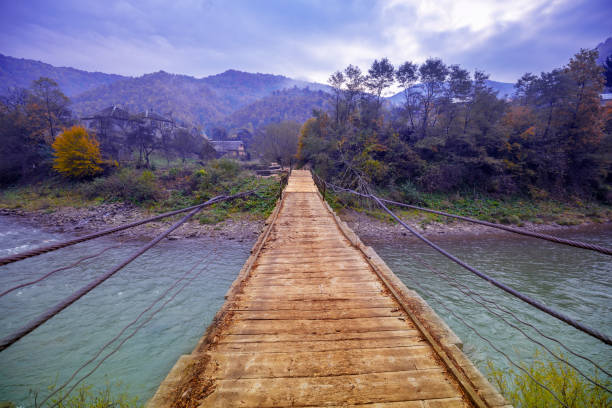 istock Hanging rope wooden bridge over mountain river 1300334904