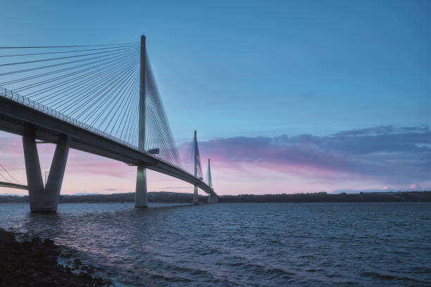 A view of a large three-tower cable-stayed bridge at sunrise stock photo