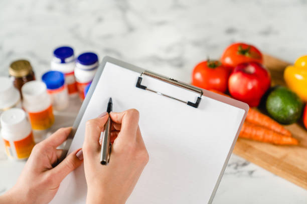 Writing on clipboard with food supplements and vegetables, healthy eating concept Writing on clipboard with food supplements and vegetables, healthy eating concept food additive stock pictures, royalty-free photos & images