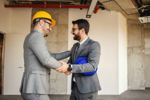 istock Smiling architect shaking hands with businessman while standing in building in construction process. 1300335453