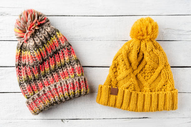 istock Colourful knitted hats on white wooden background. Top view 1300336332